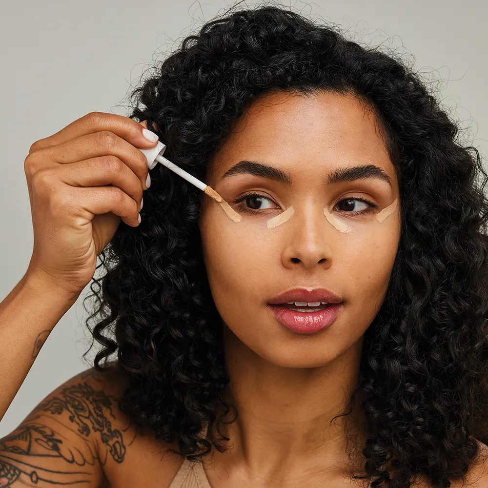 Model trägt Concealer auf