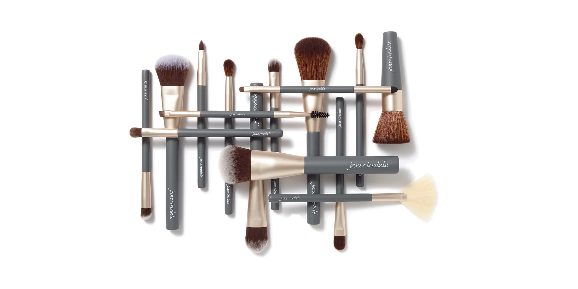 Verschiedene jane iredale Make-up-Pinsel für Gesicht, Augen und Brauen sind überlappend auf weißem Hintergrund angeordnet.