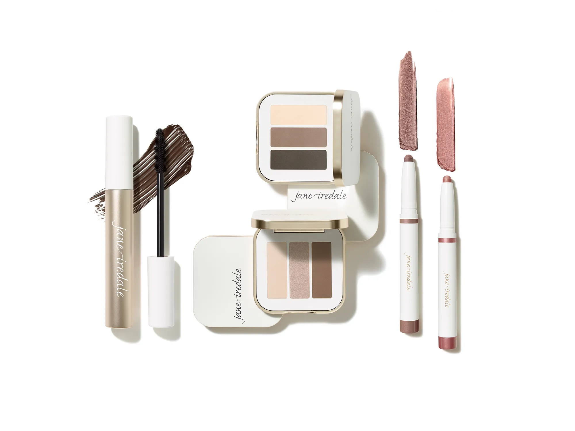 Auswahl an jane iredale Augen-Make-up-Produkten auf weißem Hintergrund: Mascara mit Bürste, zwei Lidschattenpaletten mit je drei Nuancen sowie zwei Lidschattenstifte mit passenden Farbswatches.