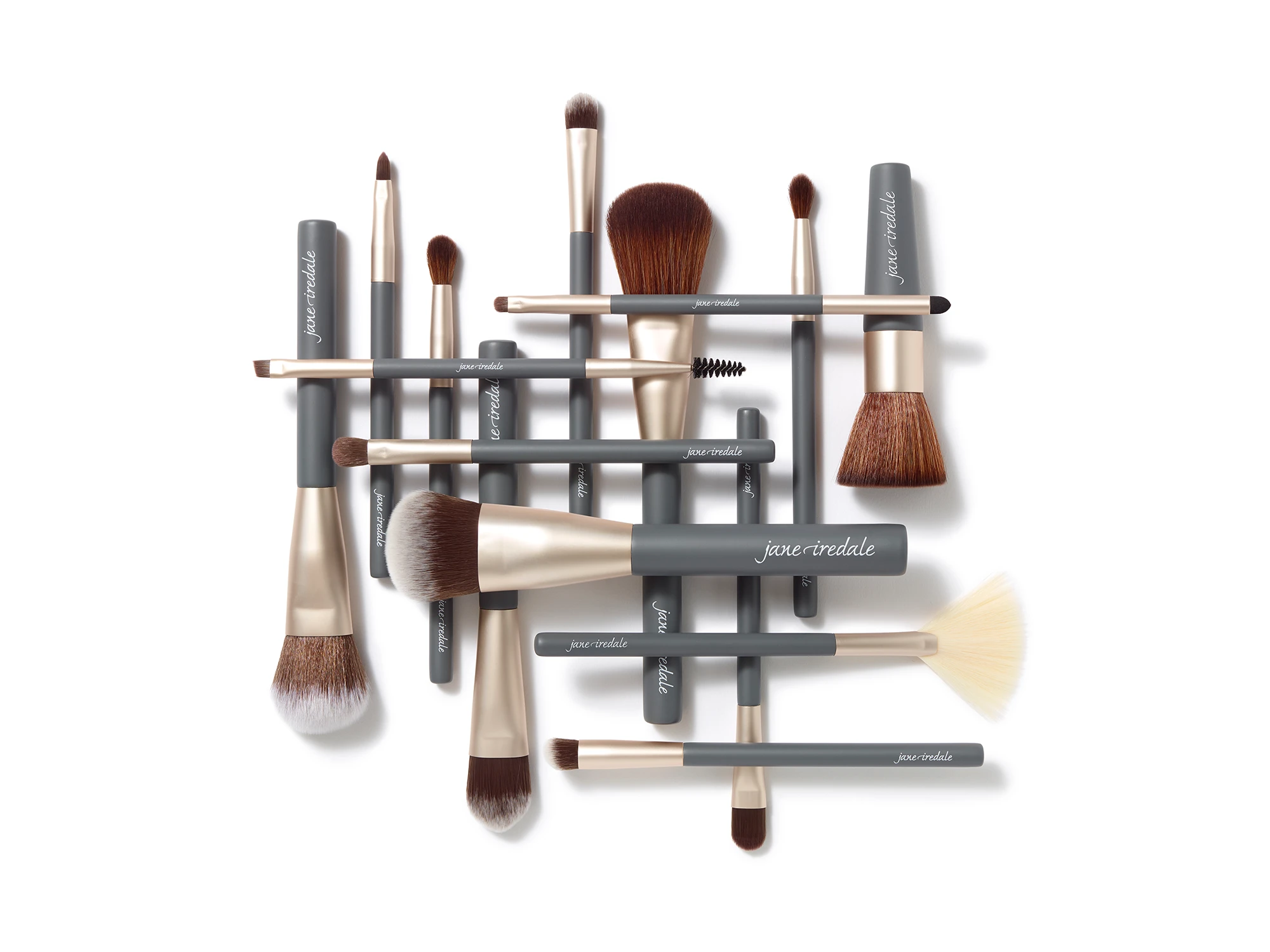 Verschiedene Make-up-Pinsel von jane iredale mit grauen Griffen und goldfarbenen Fassungen, darunter Puder-, Lidschatten- und Fächerpinsel sowie ein Augenbrauenbürstchen.